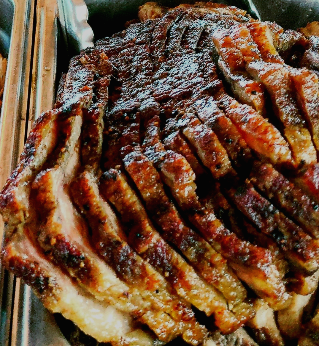 Sliced smoked beef brisket with a caramelized crust and visible marbling, showing juicy, tender texture.