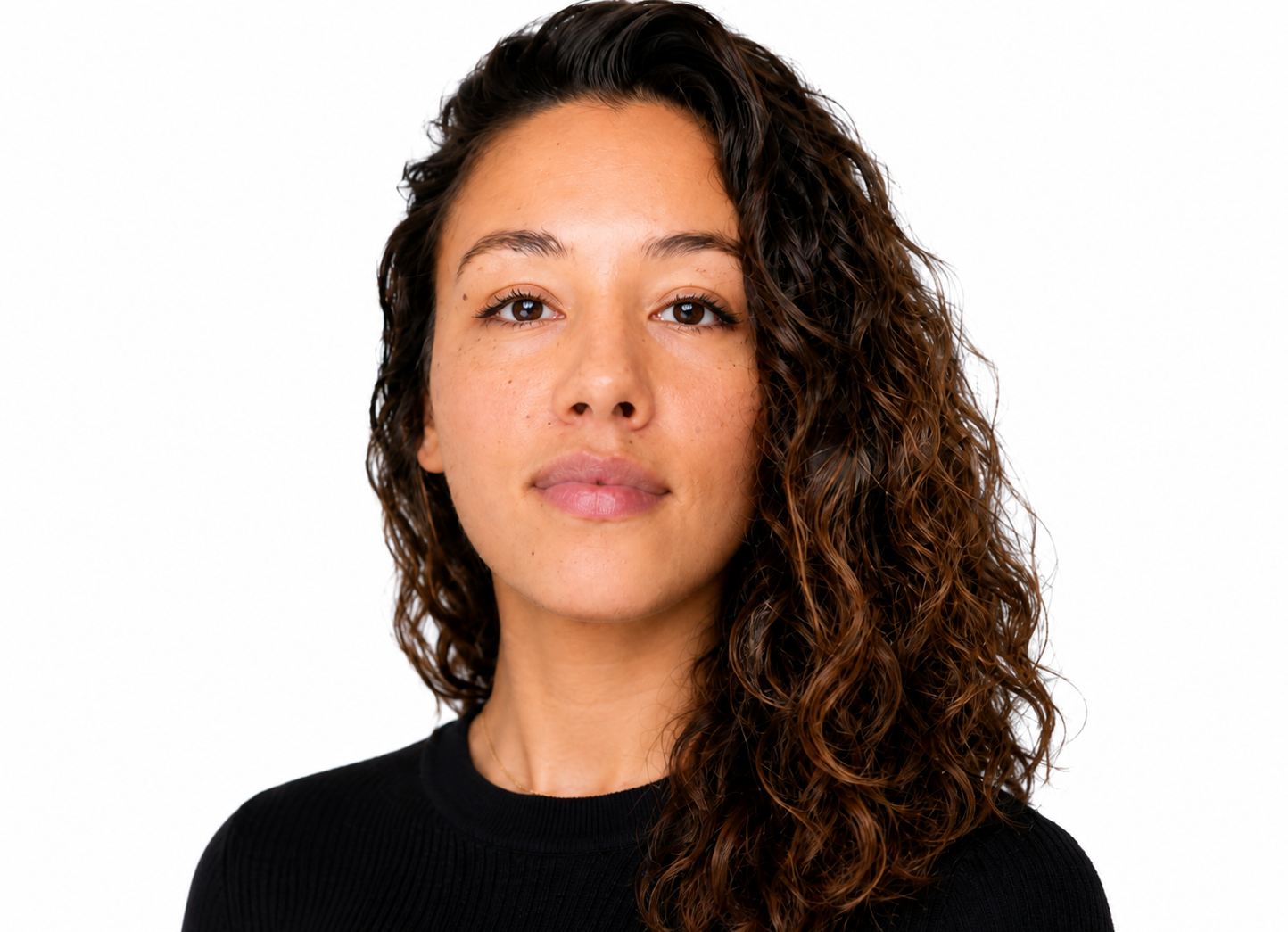 Portret van een vrouw met krullend donker haar, gekleed in een zwarte top, tegen een witte achtergrond.