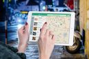 Woman using a tablet, displaying a map and food search results, in a night street setting.