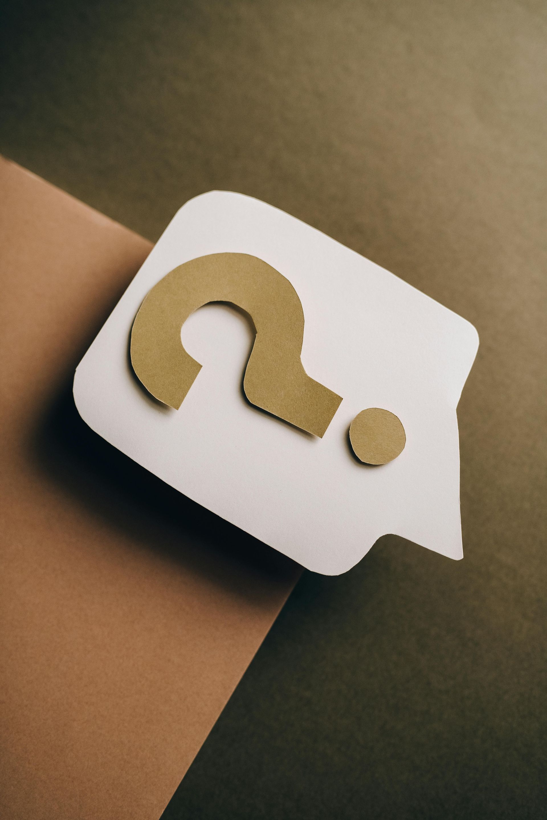White speech bubble with gold question mark on brown and green backgrounds.