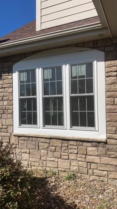 A house with three builder grade windows on the side of it.