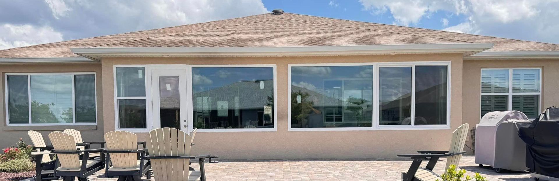 The back of a house with a lot of windows and a grill.