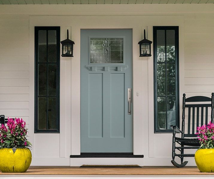 A front porch with a blue door and a rocking chair