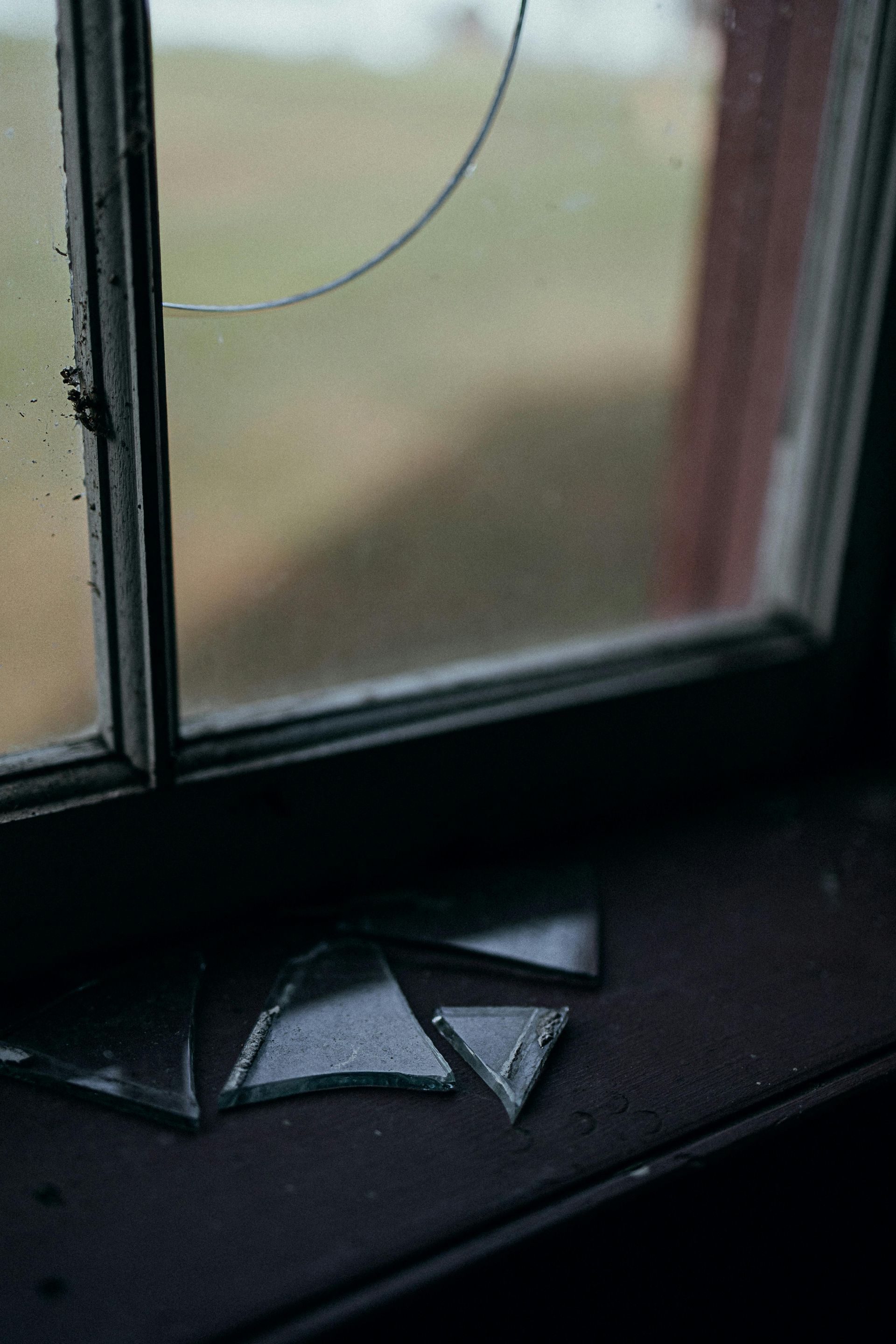 Broken window pane with shards on a dark windowsill
