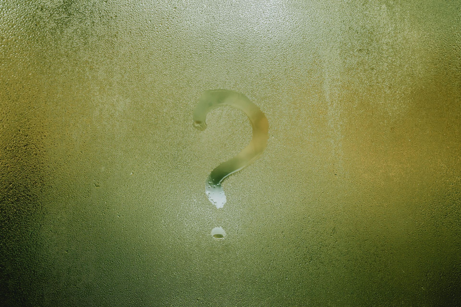 Question mark wiped on a foggy, green-tinted window.
