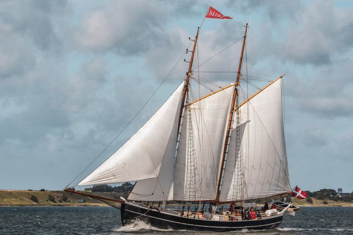 En stor sejlbåd sejler fuld sejl langs kysten