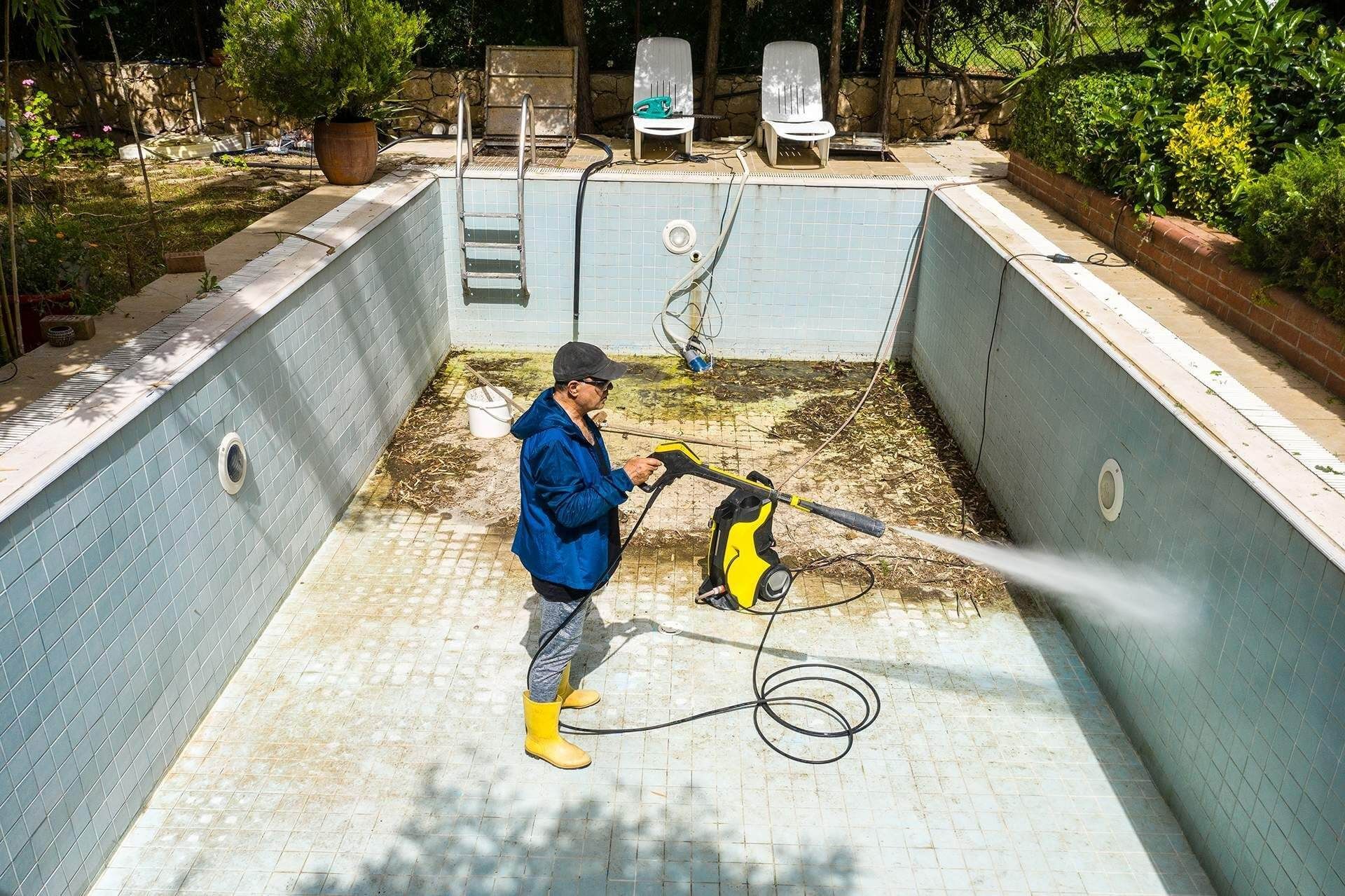 a man is cleaning a swimming pool with a high pressure washer