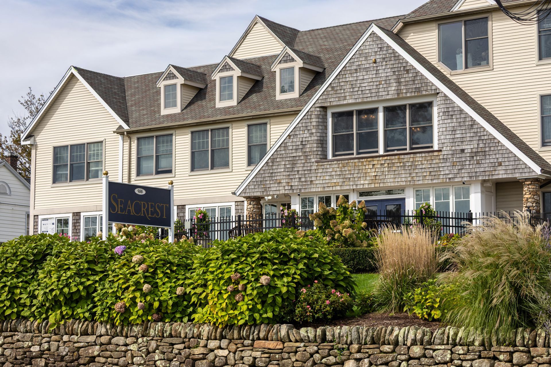 Seacrest Retirement Center exterior; beige building with stone wall and manicured landscaping under a cloudy sky.