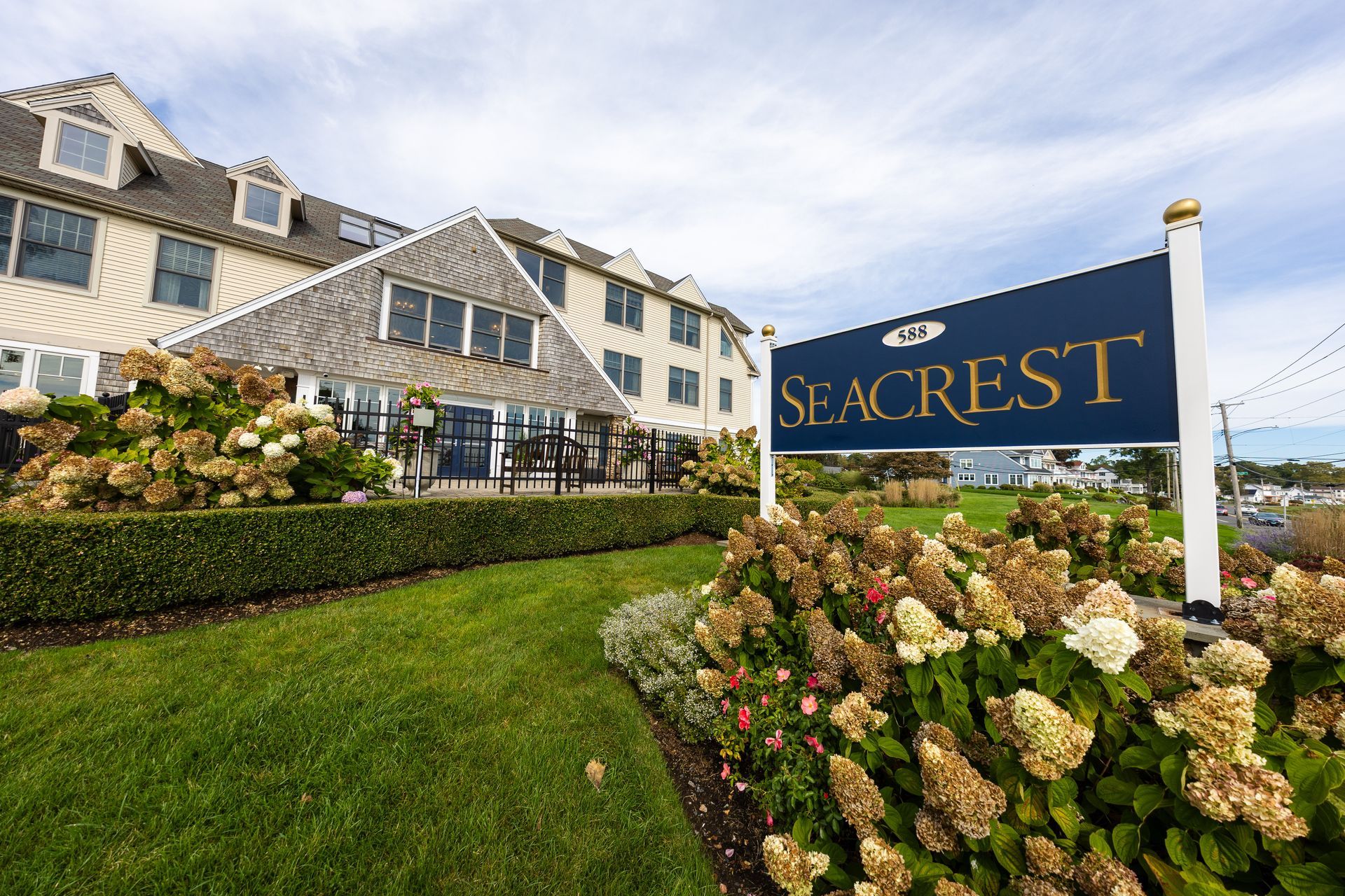 Seacrest Retirement Center exterior; beige building with stone wall and manicured landscaping under a cloudy sky.