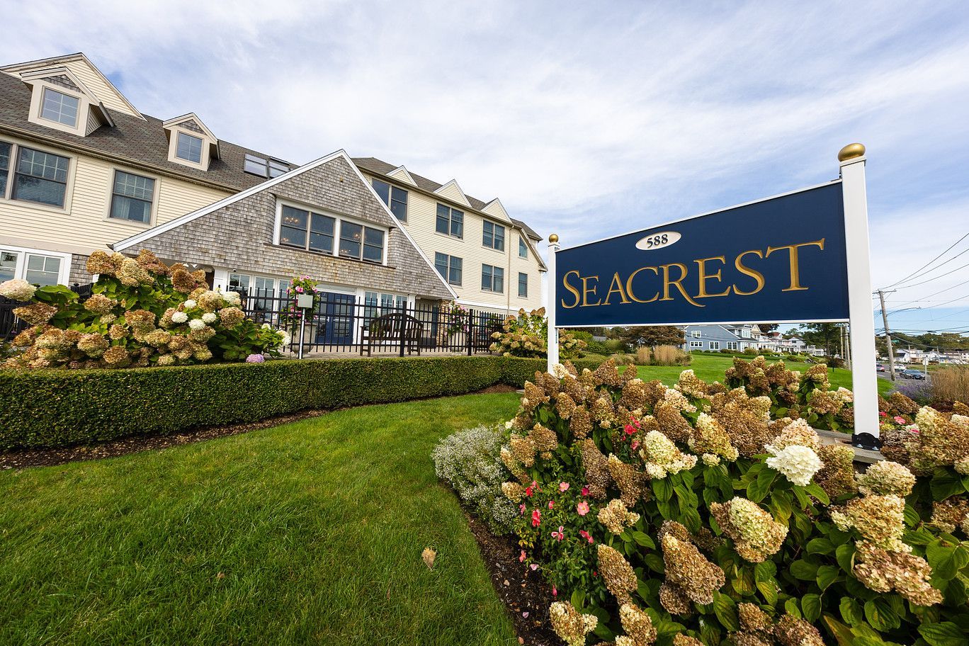 Seacrest resort sign beside a flowered lawn and white seaside building under a cloudy sky