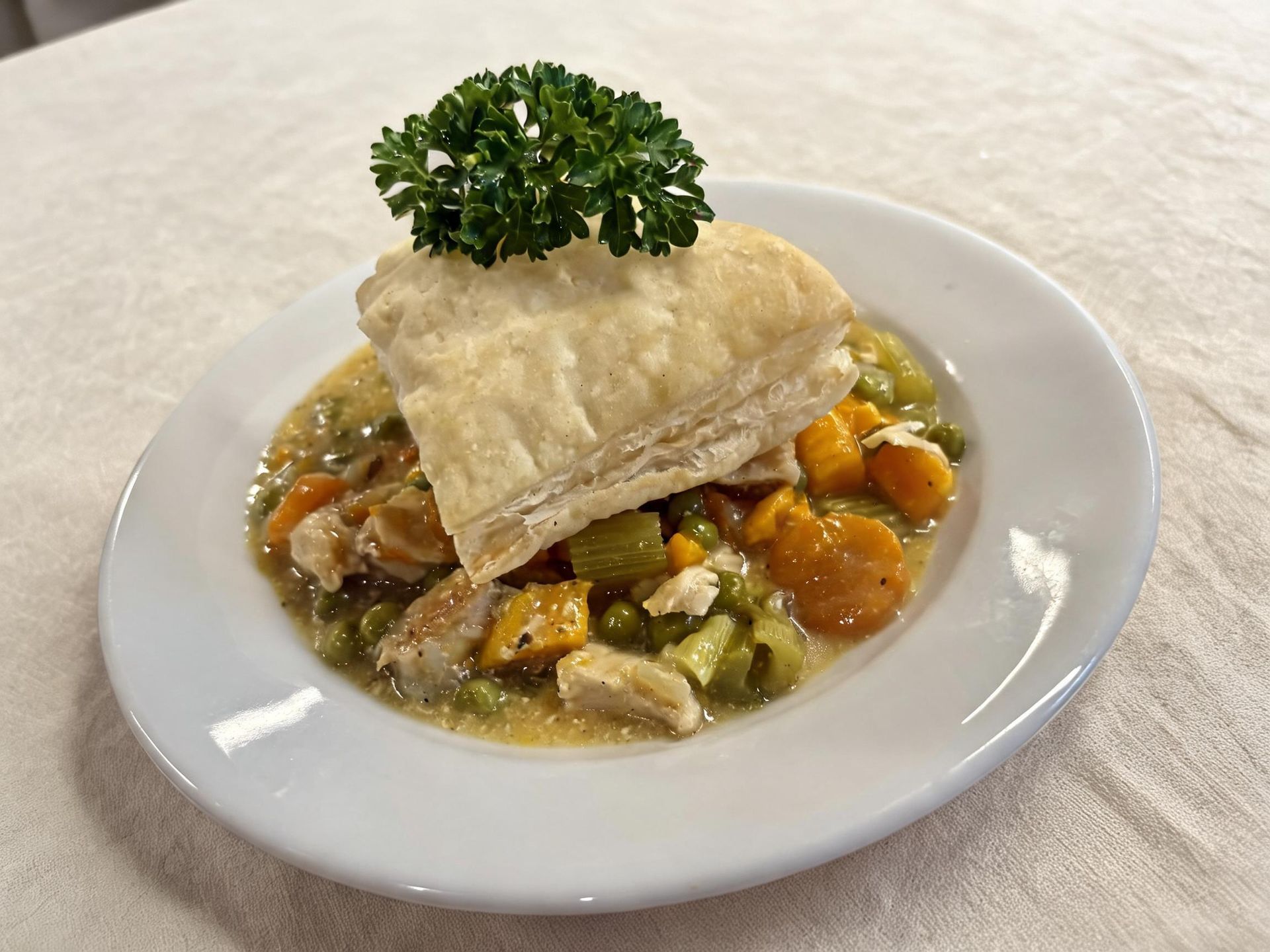 Plated gourmet appetizer with creamy stew, vegetables, and a crisp garnish topped with parsley