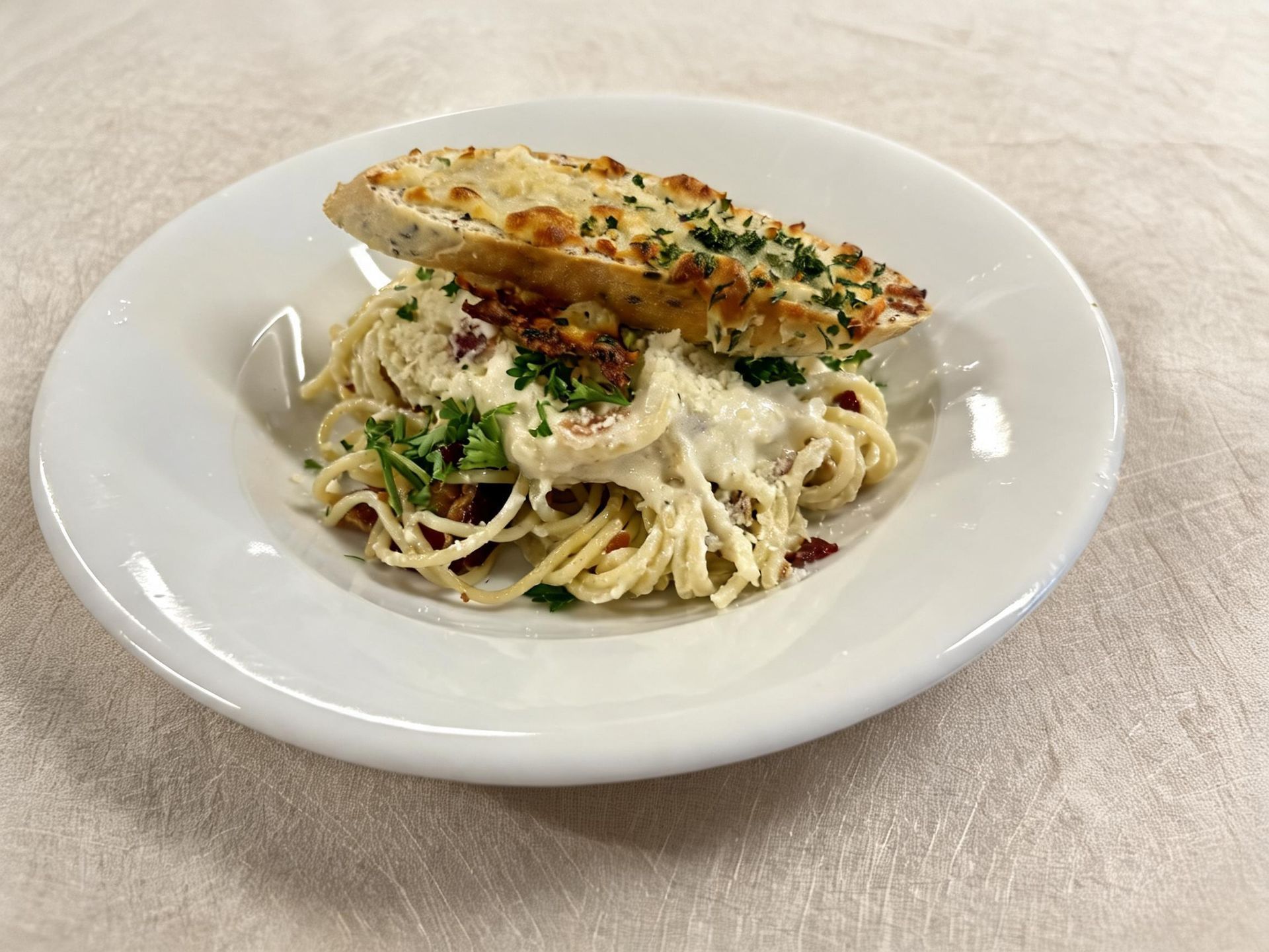 Plate of creamy pasta topped with grilled chicken and herbs on a white dish