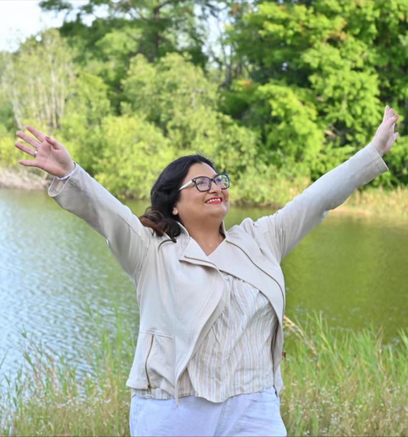 Woman smiling at desk, large book open, artwork on wall.