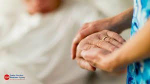 A caregiver holds the hand of a patient, providing comfort and support.