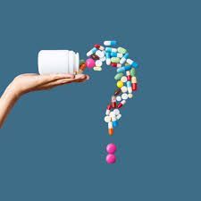 Hand pouring pills from a bottle, forming a colorful question mark. Blue background.
