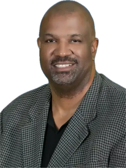 Man with a shaved head and a gray and black patterned blazer smiling at the camera.