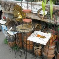 A collection of tiered wire plant stands, terracotta pots, and a decorative tile featuring a bee in a garden store.