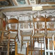 A collection of wooden chairs and a wooden step stool displayed on shelving in a shop.