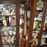 Two dark wooden china cabinets filled with a dense collection of assorted glassware, ceramic figurines, and ornaments.