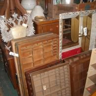 A collection of vintage items including wooden printer's trays, a decorative eagle crest, and a mirror in a cluttered shop.