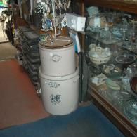 A stack of two antique ceramic stoneware crocks, with a blue floral design and the number 10, sitting in a shop.