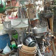 A collection of vintage metal containers, buckets, and funnels hanging and stacked in an outdoor display.