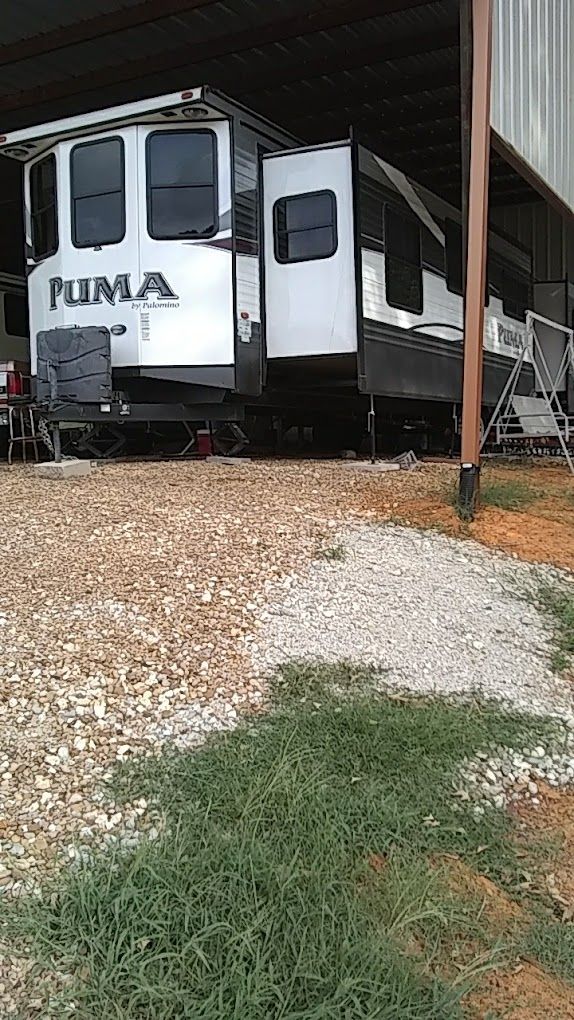 A white rv is parked under a shed.