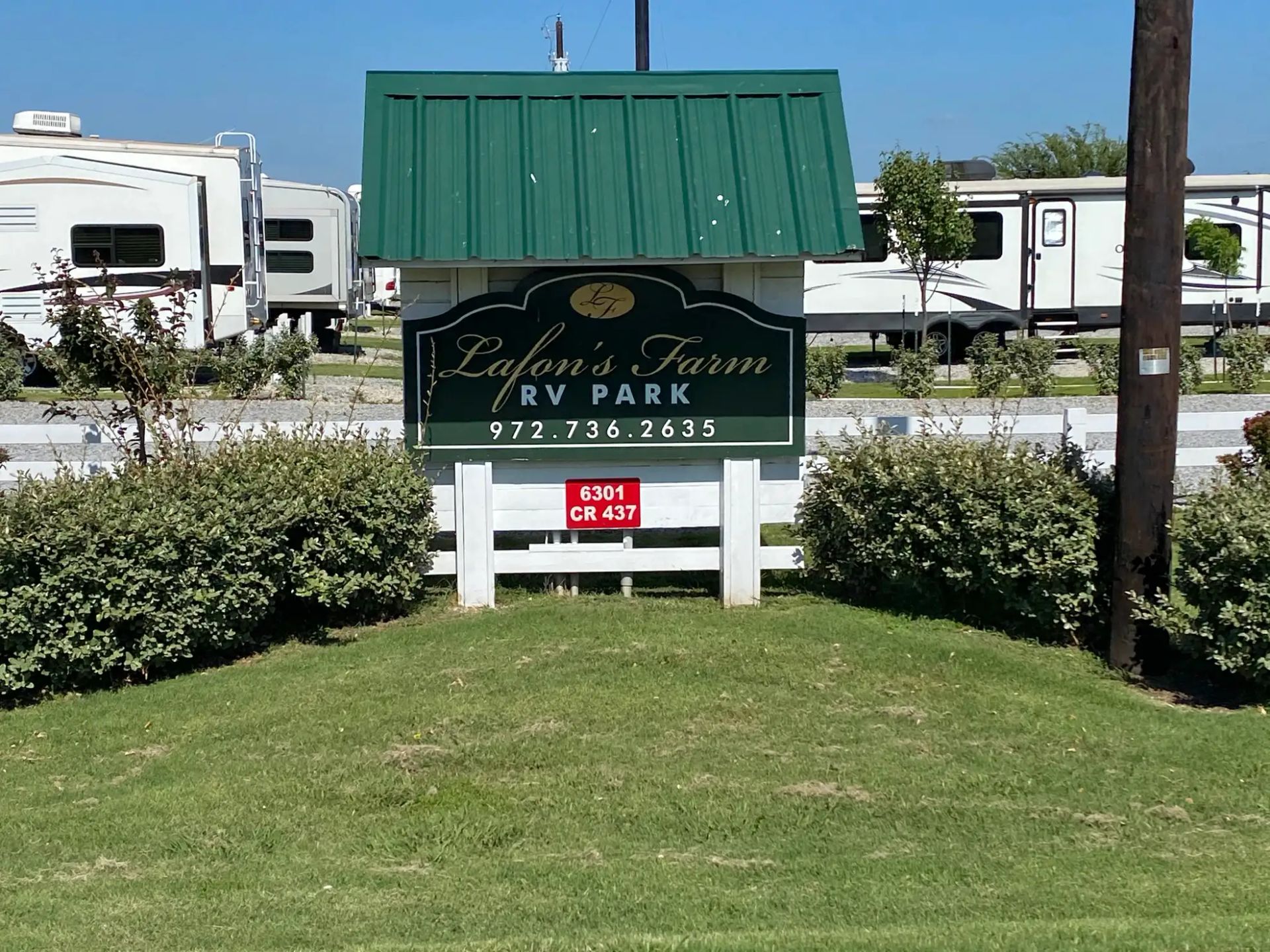 A white rv is parked under a shed.