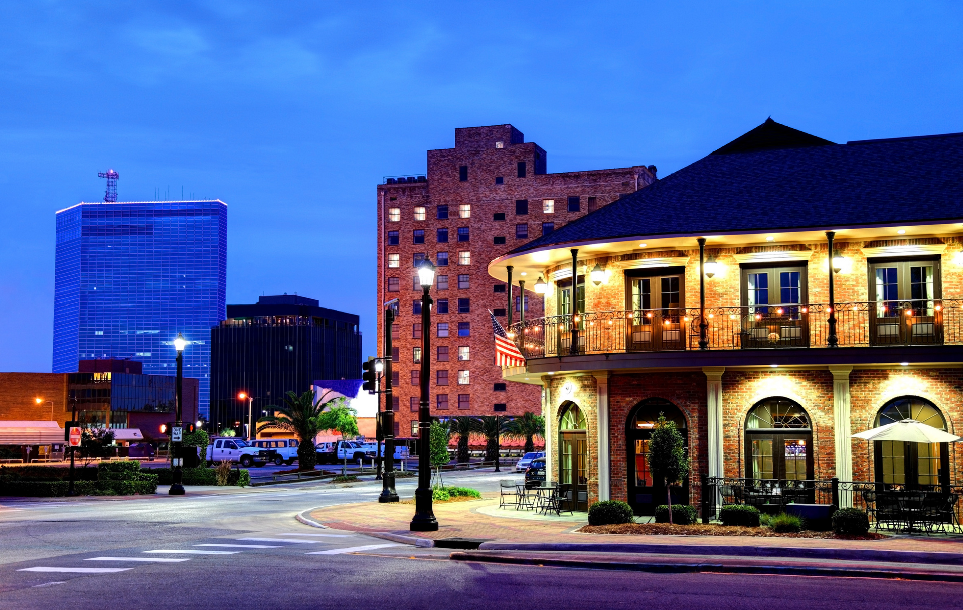 An evening photograph of a historic Texas downtown street with brick buildings and illuminated balconies