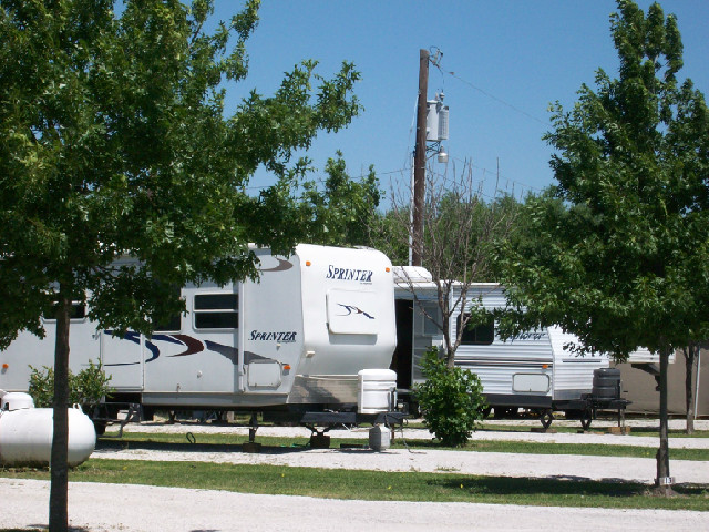A white rv is parked in a lot with trees