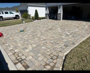 Driveway paved with tan and gray interlocking pavers. A white truck is parked in the driveway.