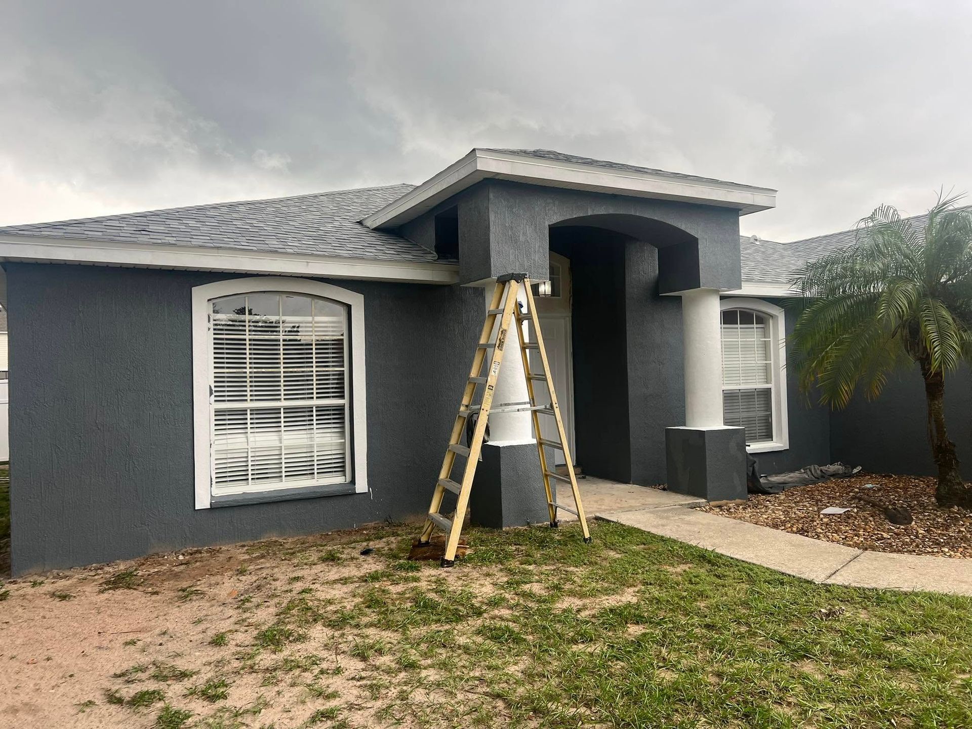 Gray house with white trim and a ladder propped against the entrance.