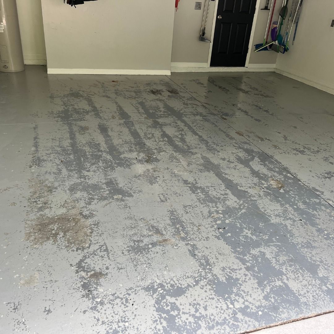 Garage floor with peeling gray paint.