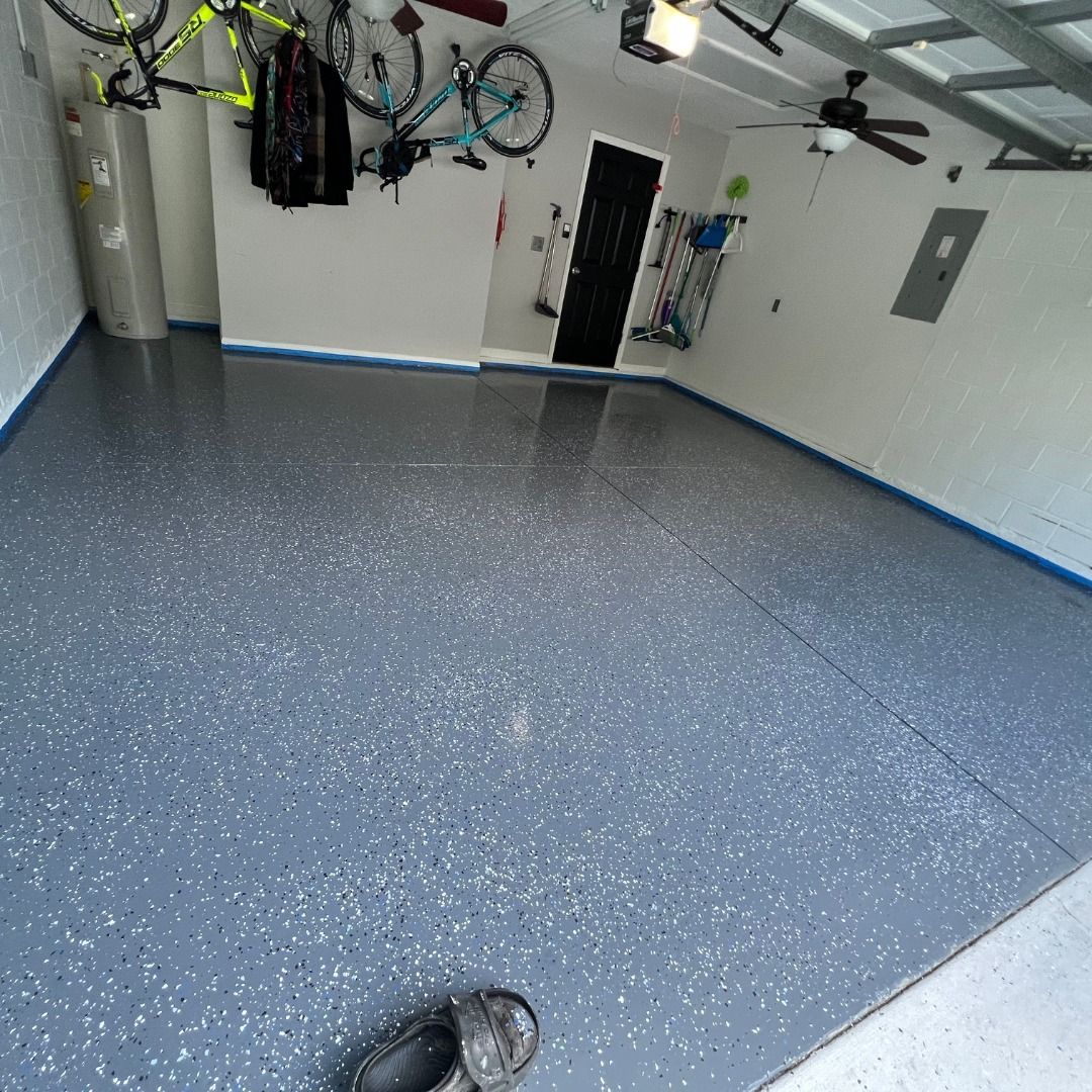 A newly finished garage floor with blue-gray epoxy, with bicycles and a water heater on the walls.