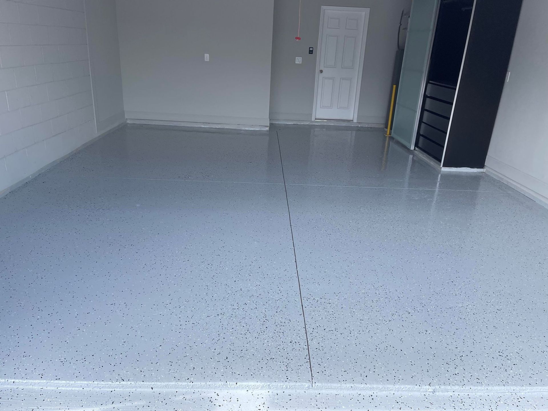 A garage with a gray epoxy floor. The floor is speckled and has a crack running through the center.