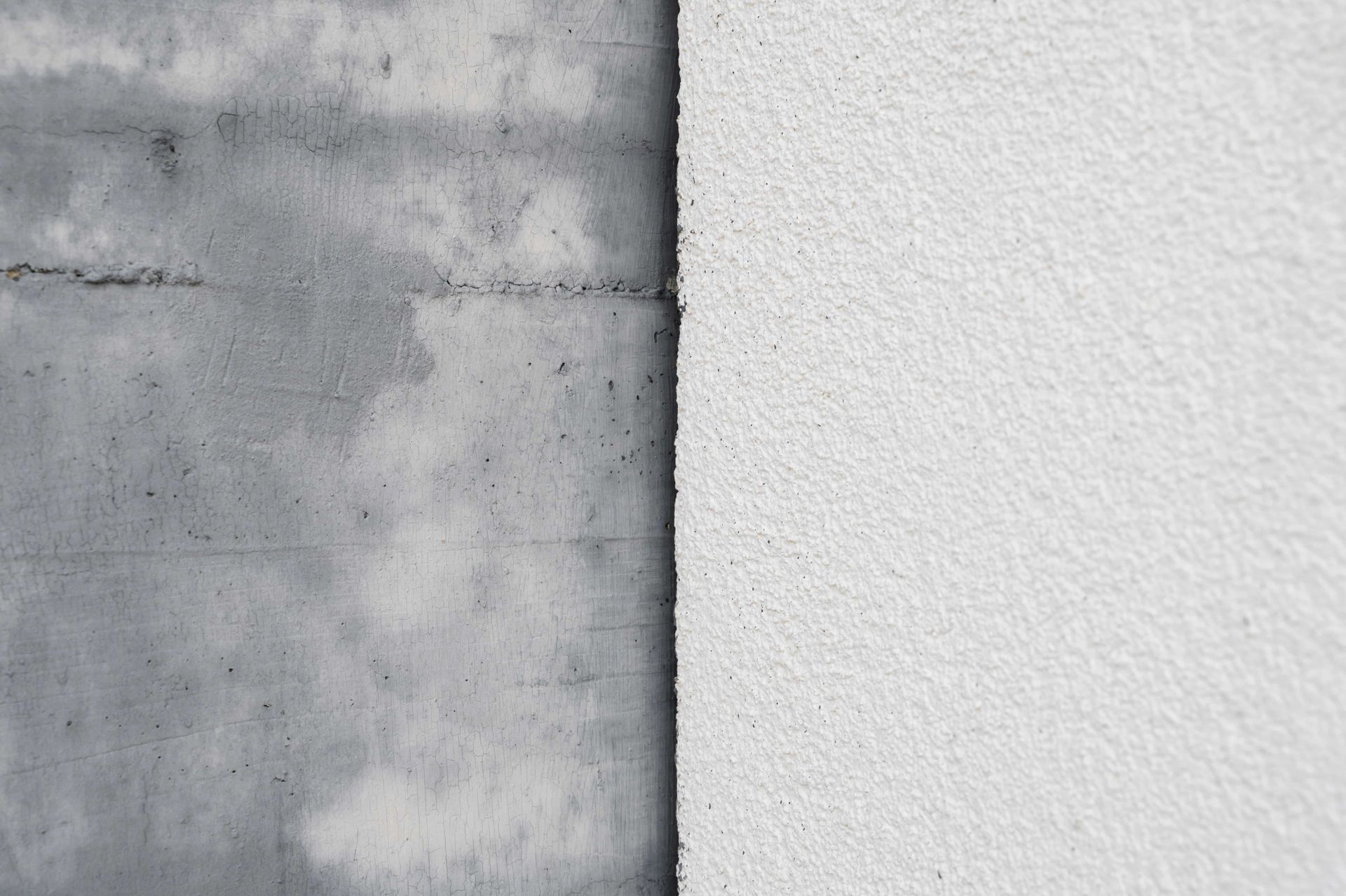 Concrete wall juxtaposed with a white, textured surface, divided vertically.