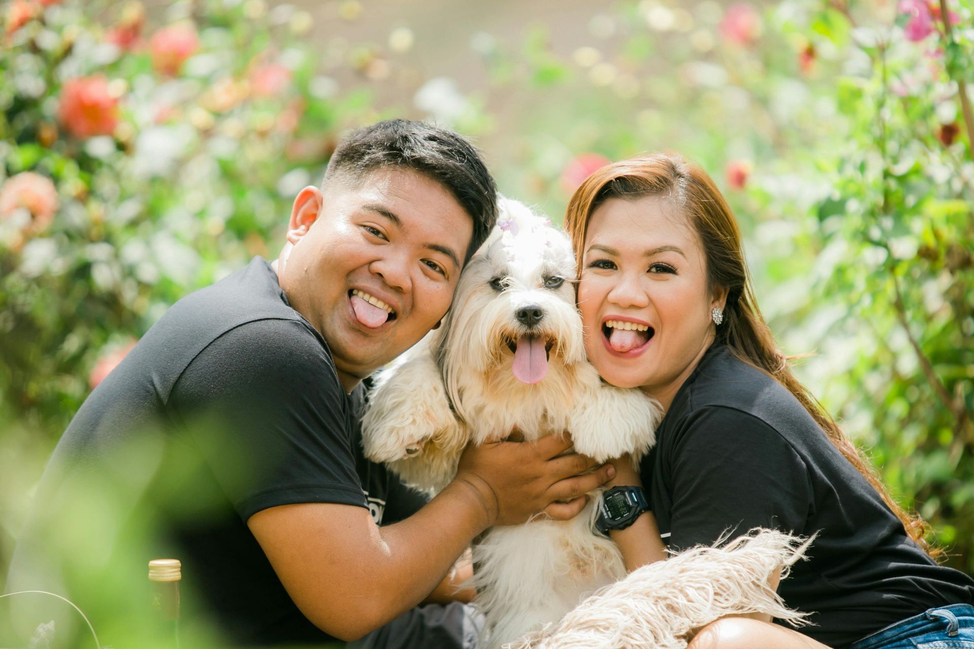 A man and a woman are holding a small white dog.