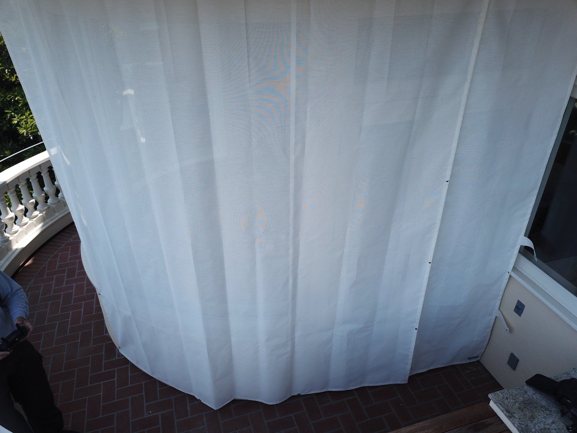 A large white curtain is hanging on a balcony