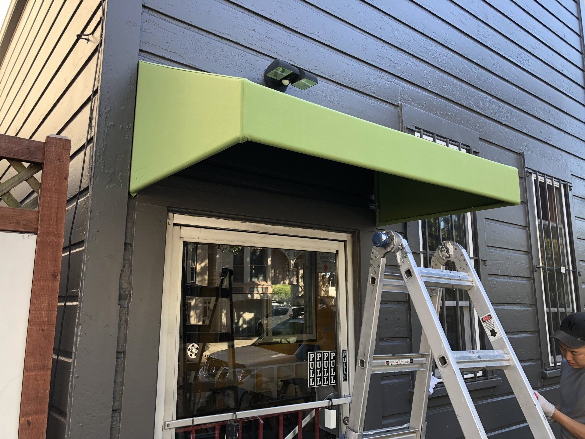 A green awning is being installed on the side of a building.