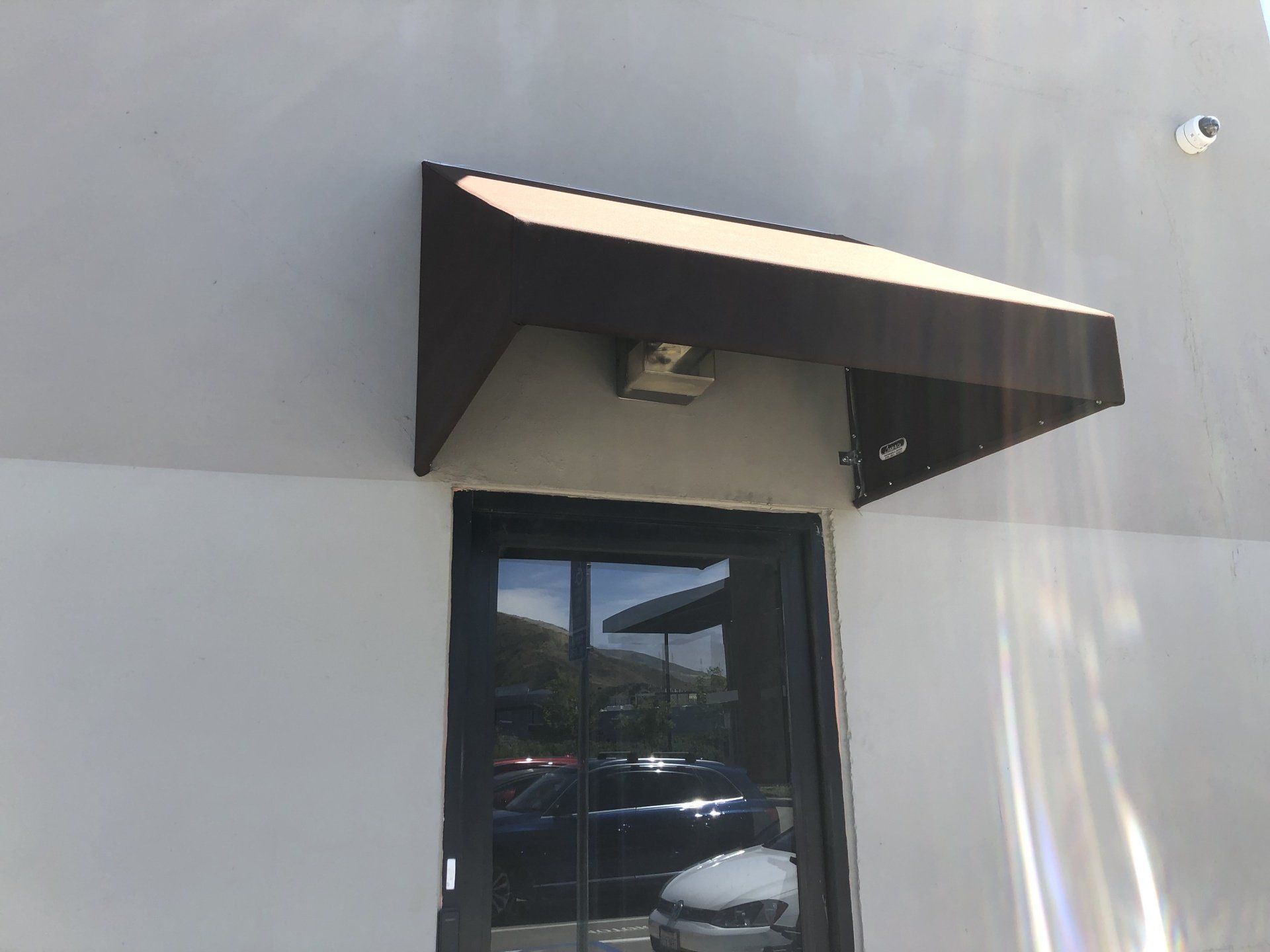 A white building with a brown awning over a door