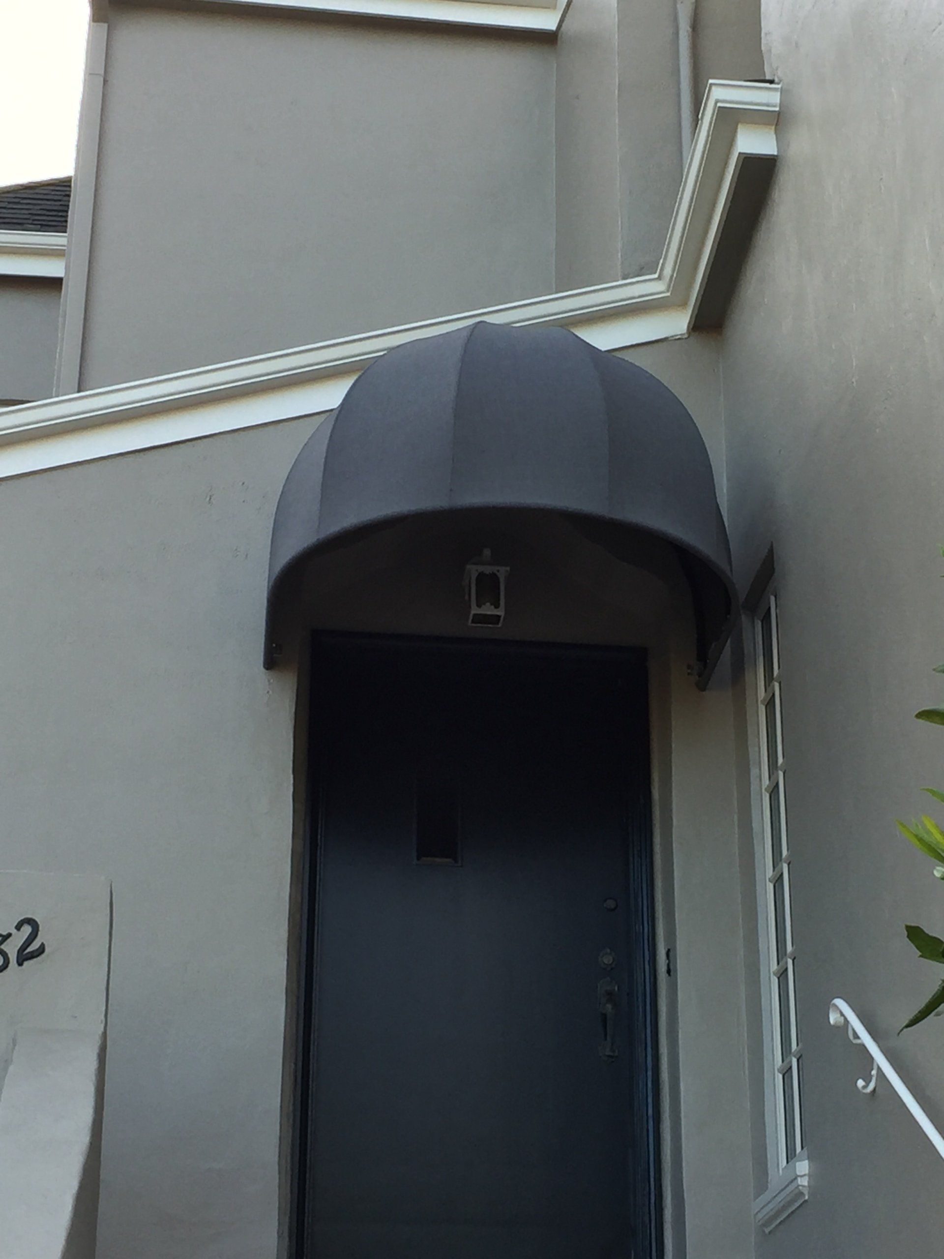 A gray building with a black awning over the door