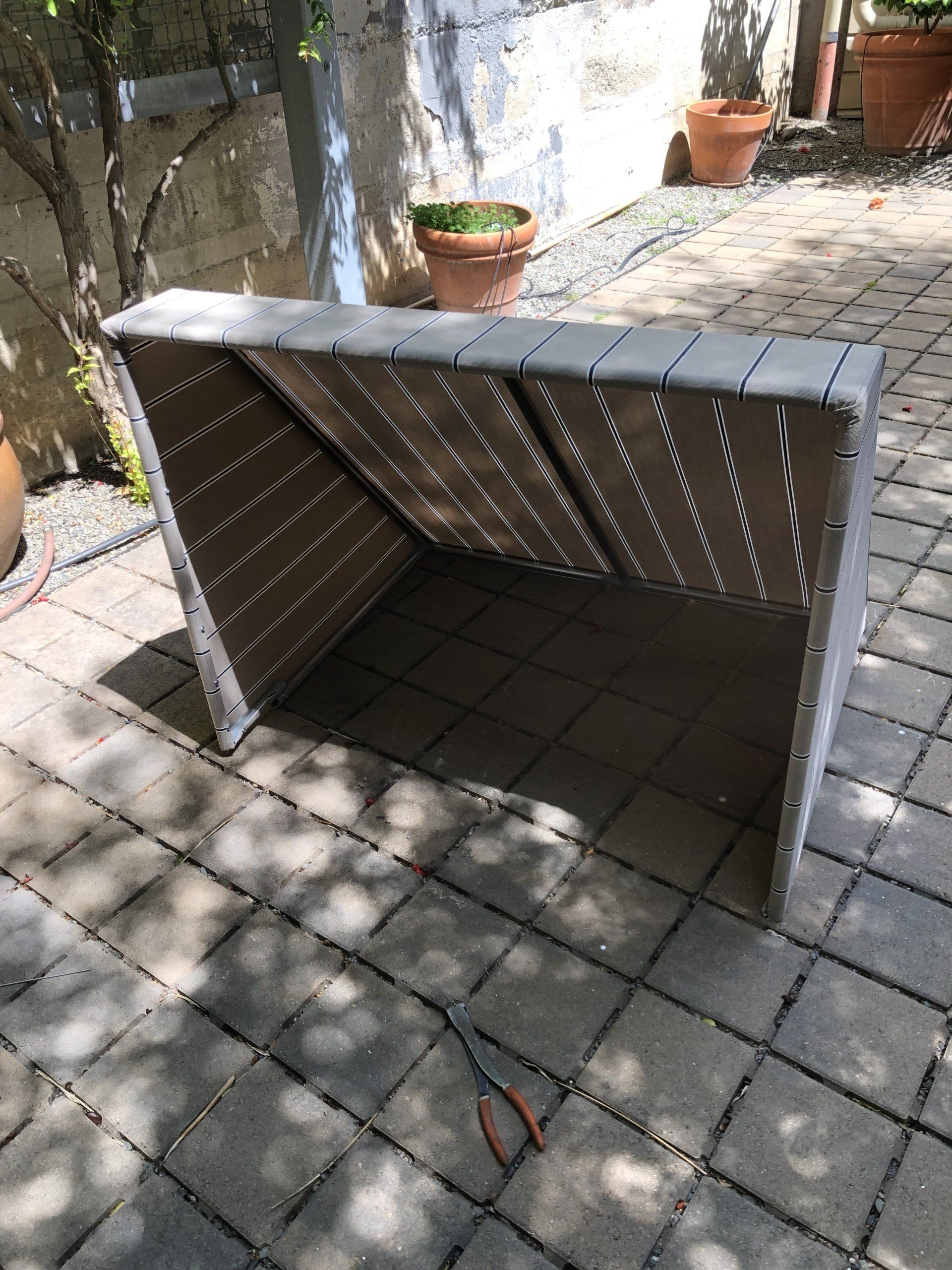 A wooden bench is sitting on a brick patio next to potted plants.