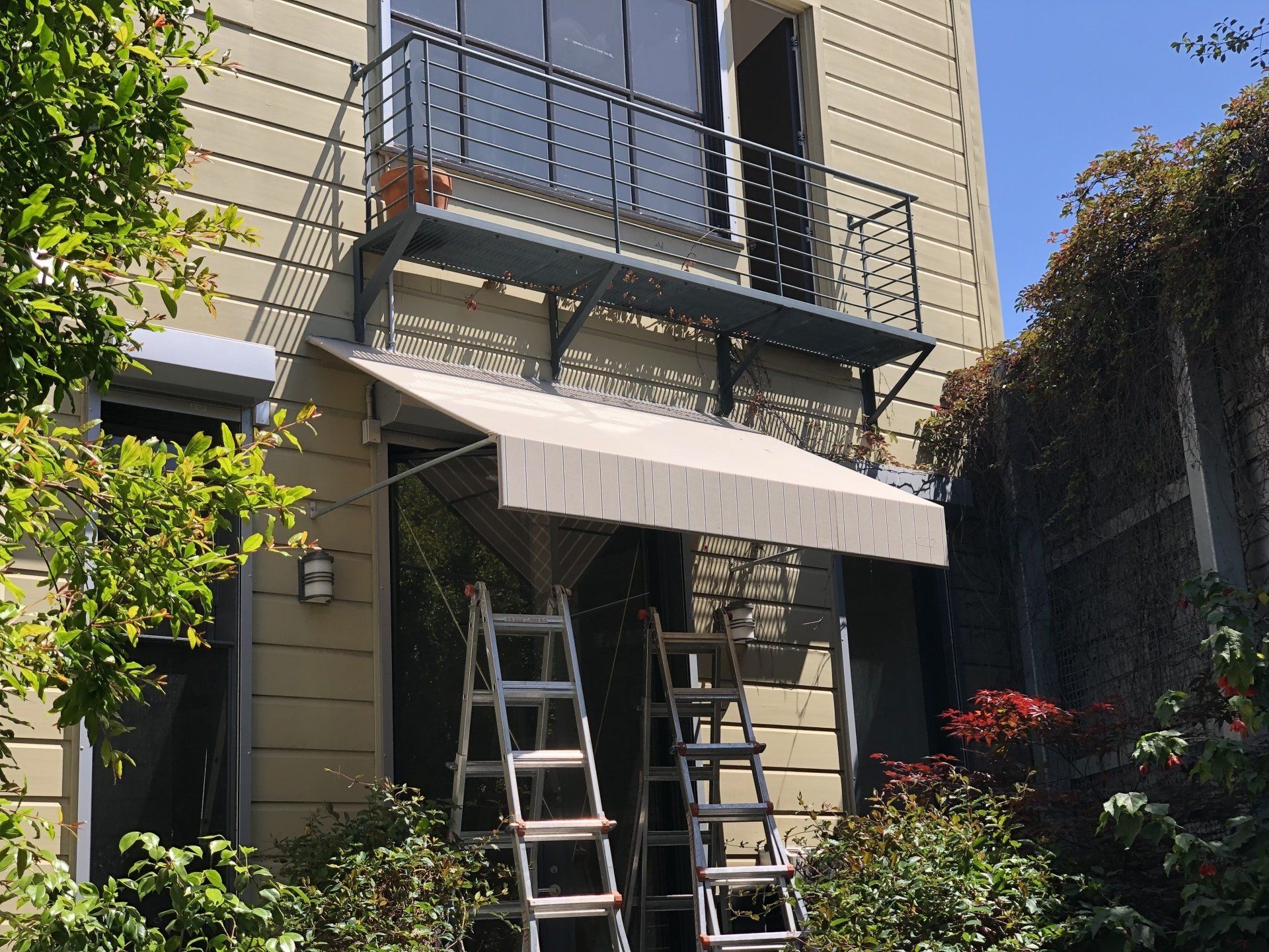 A ladder is sitting under an awning on the side of a building