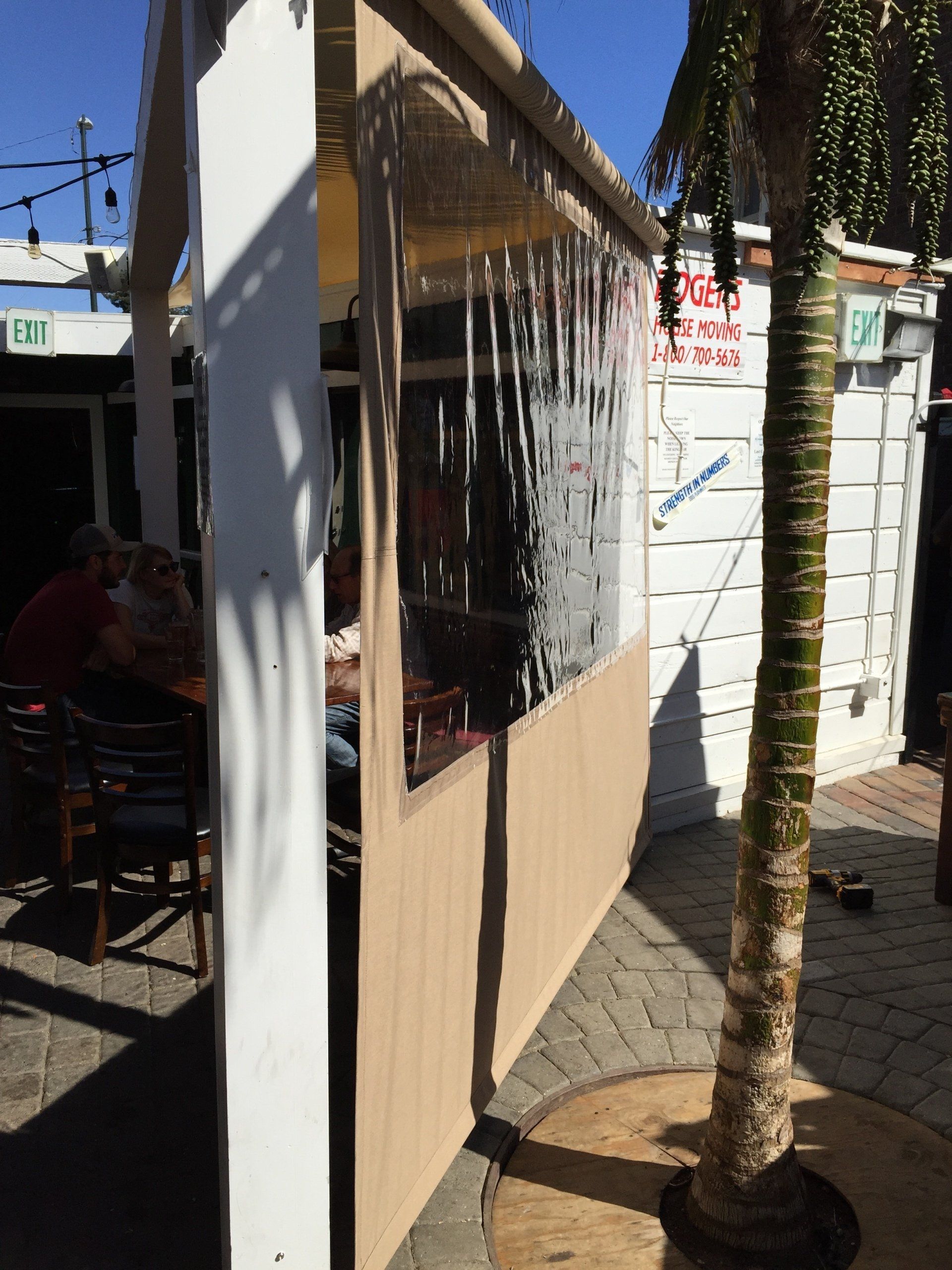 A group of people are sitting at a table under a clear canopy.