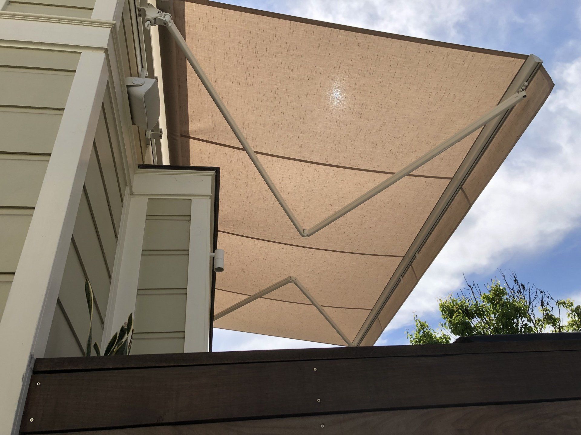 A tan awning is on the side of a house