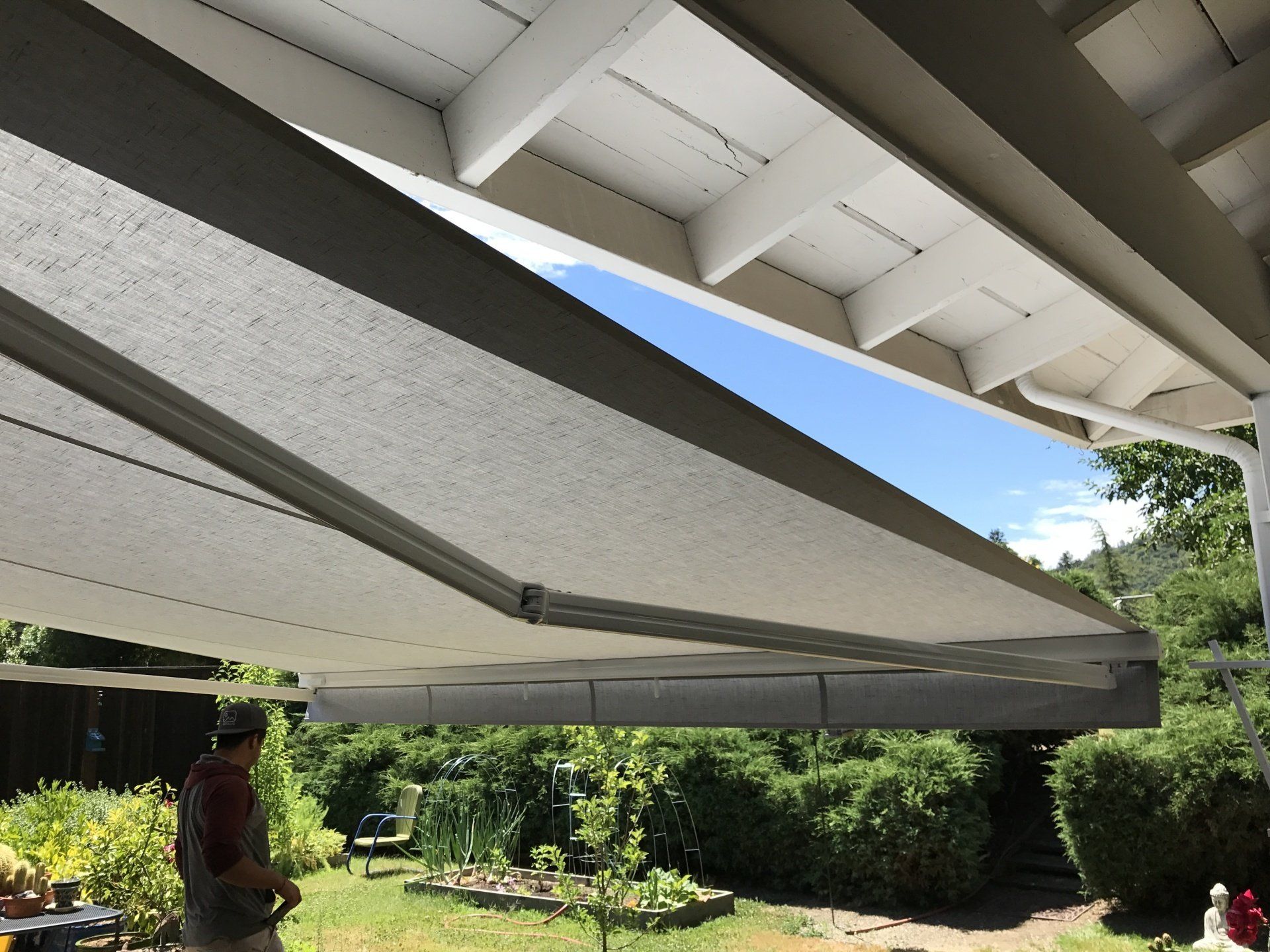 A man is standing under an awning in a backyard