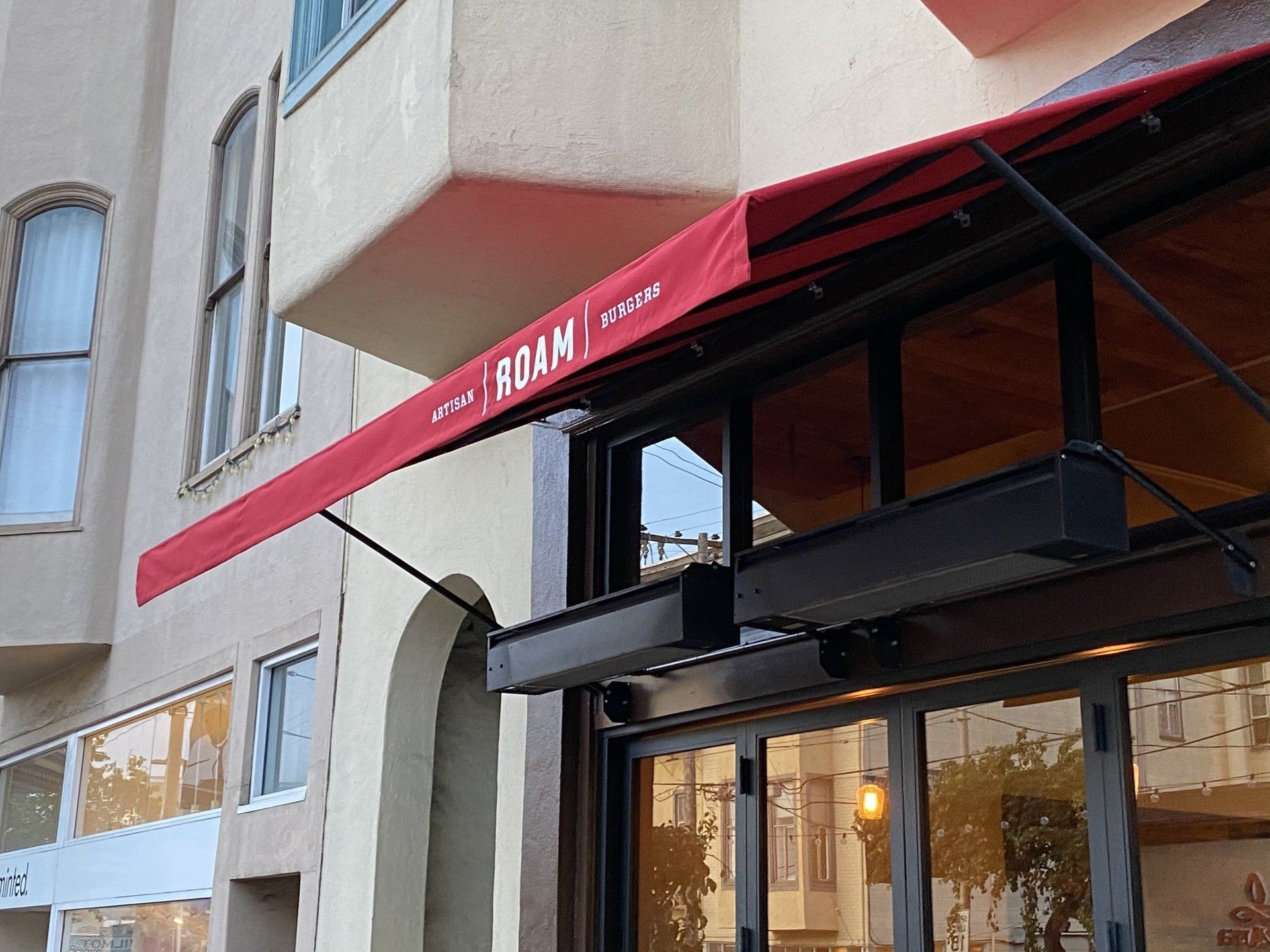 A store front with a red awning that says roam on it