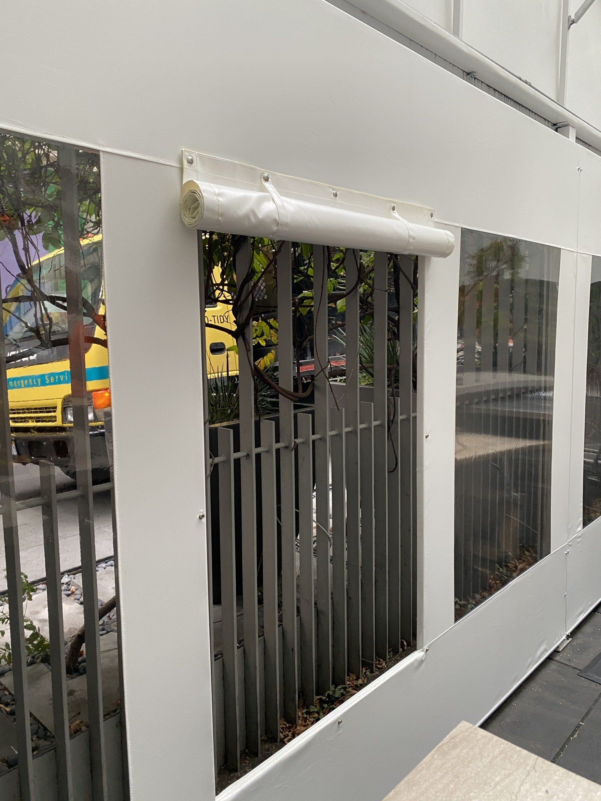 A white fence with a reflection of a car in the window.