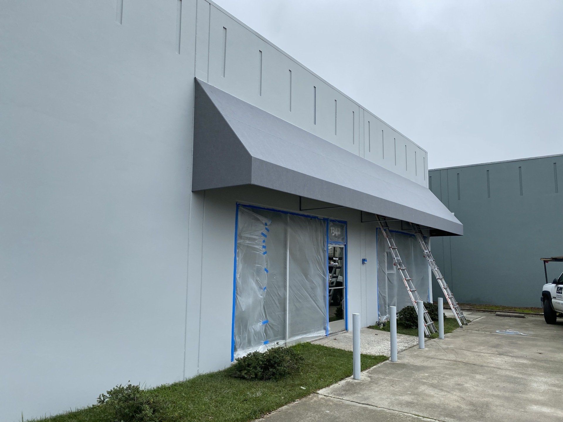 A white building with a gray awning on the side of it.