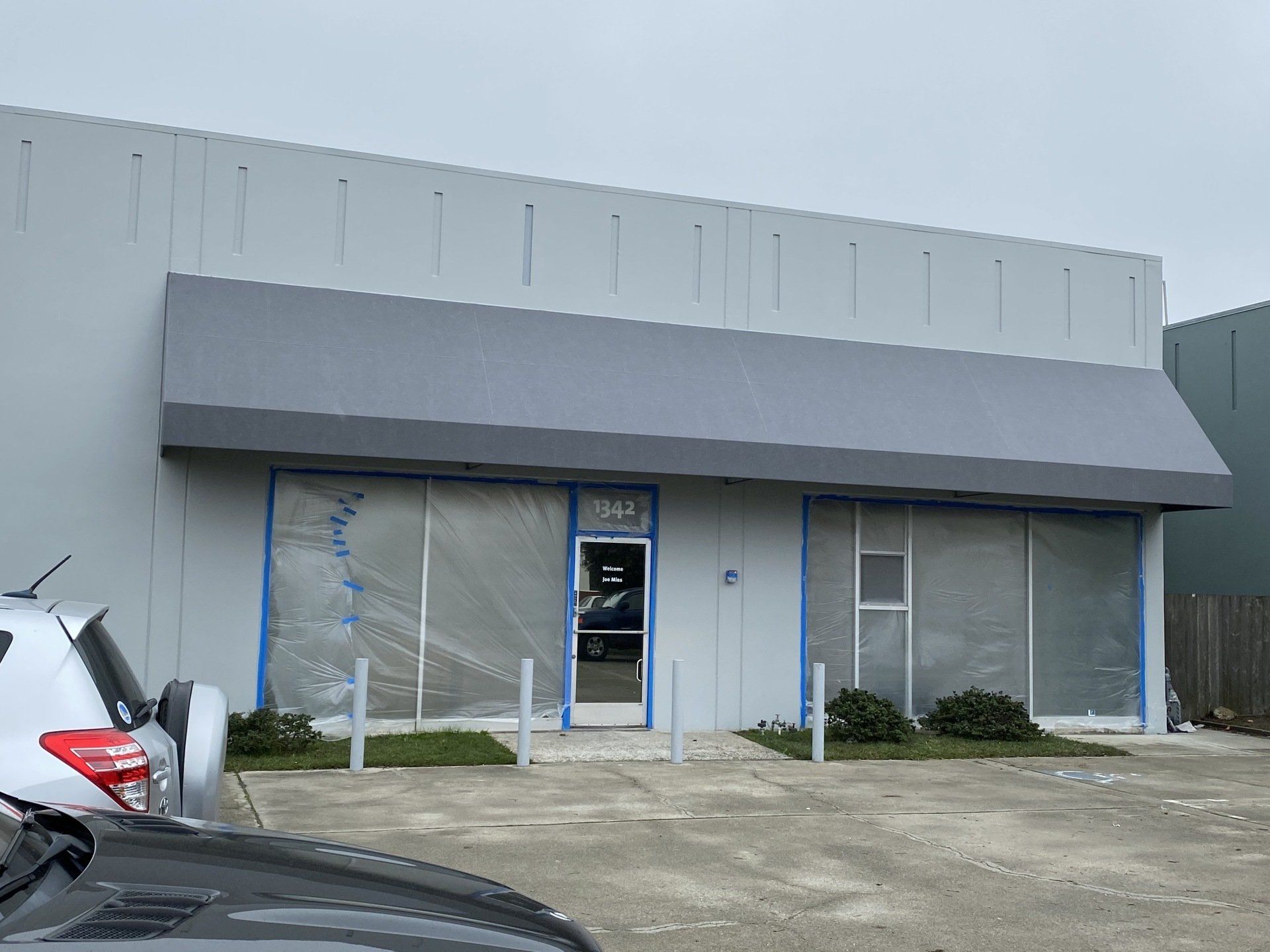 A car is parked in front of a building that is being painted.